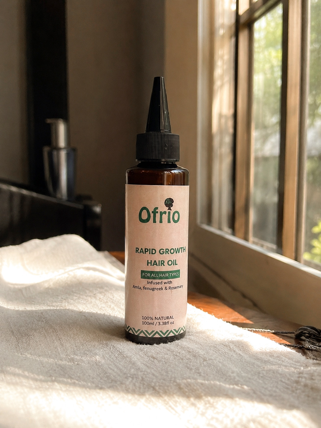 Ofrio Rapid Growth Hair Oil on a bed near a window